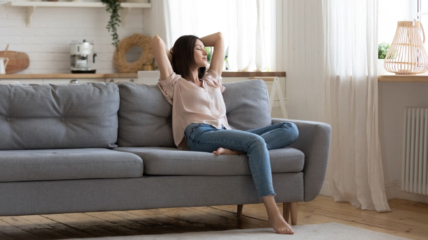 Woman sits on couch basking in the fresh smell of her home